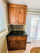 Kitchen with dark stone countertops, light tile patterned floors, and wood finish cabinetry
