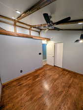 Unfurnished bedroom featuring lofted ceiling with beams, wood finished floors, and ceiling fan
