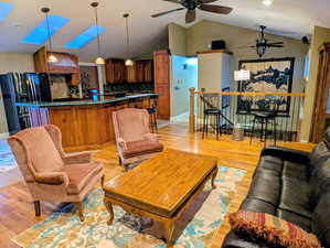 Living room featuring light wood-style floors, ceiling fan, and a skylight