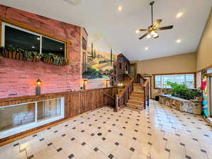 Living area with ceiling fan, wood walls, lofted ceiling, recessed lighting, and a wainscoted wall