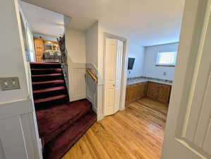 Stairway featuring hardwood / wood-style flooring, wainscoting, and a textured ceiling