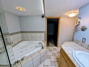 Full bath featuring vanity, a textured ceiling, and a whirlpool tub