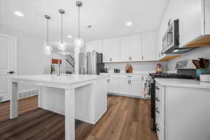 Kitchen with stainless steel appliances, dark wood finished floors, a kitchen island with sink, and white cabinetry