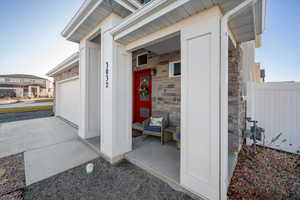 Property entrance featuring stone siding, an attached garage, driveway, and covered porch