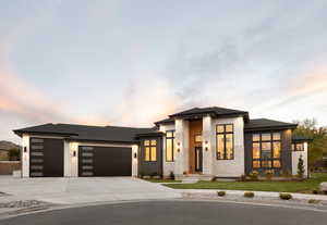 View of front of house featuring stone siding, an attached garage, driveway, and roof with shingles