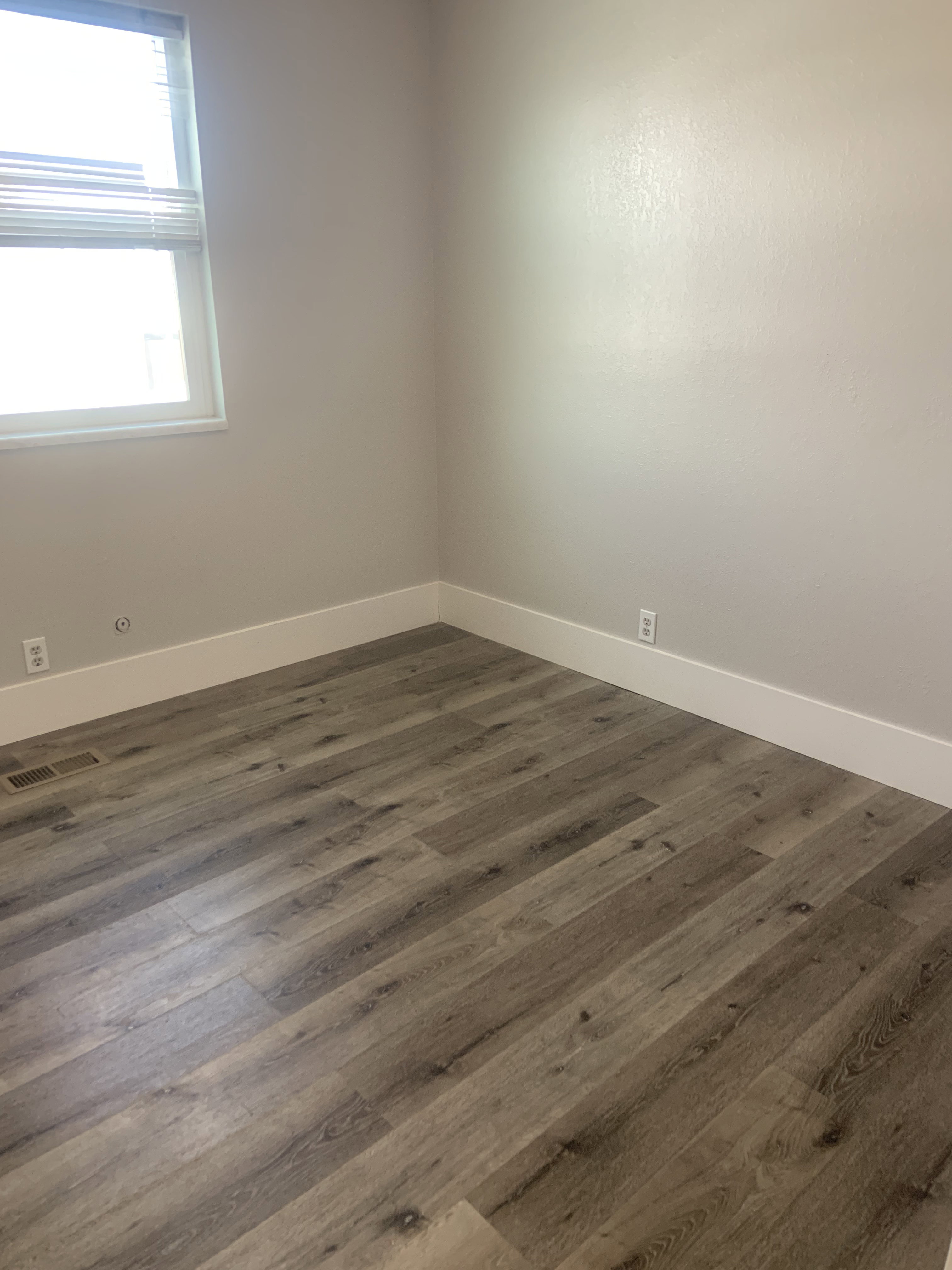 Wood-finish flooring complemented by neutral wall tones, white trim, and window blinds