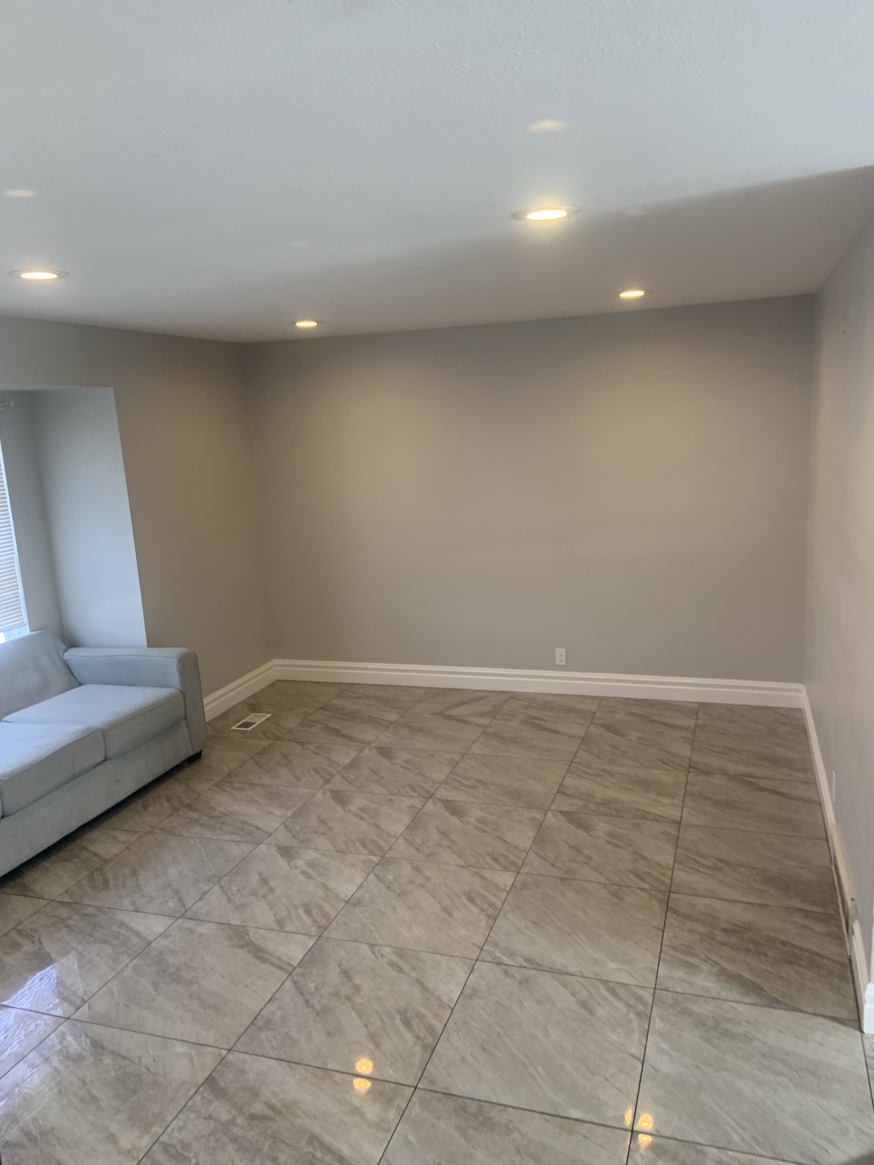 Spacious room featuring large format tile flooring, recessed ceiling lighting, and crisp white baseboards