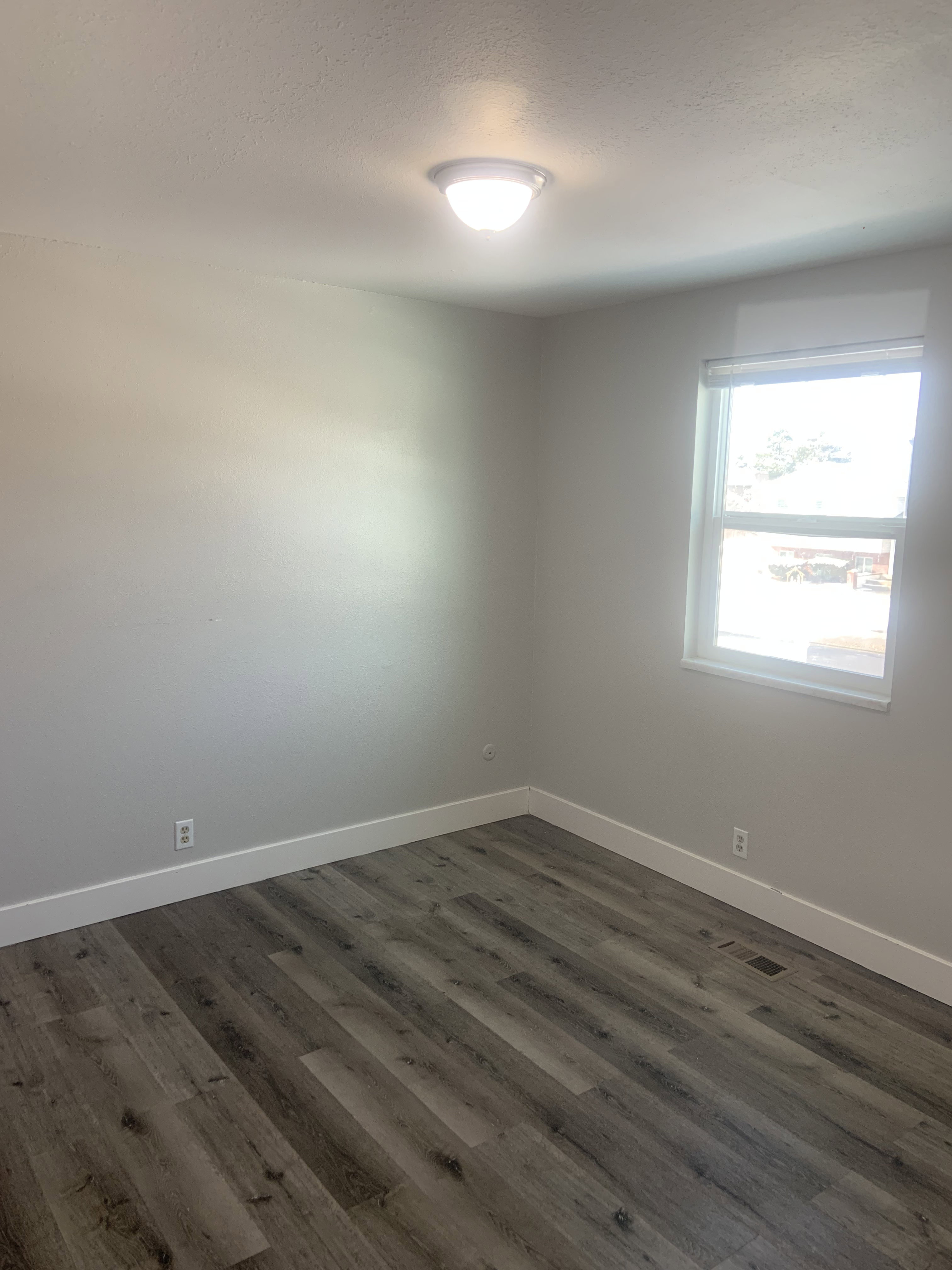 Room featuring wood-finish flooring, white baseboards, and neutral wall tones