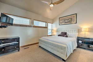 Bedroom featuring vaulted ceiling, light colored carpet, and a ceiling fan