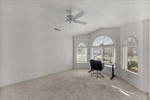 Home office with carpet floors, a ceiling fan, and vaulted ceiling