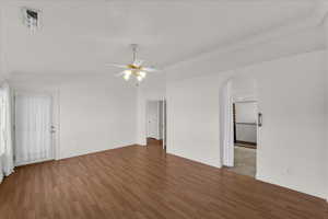 Empty room featuring ornamental molding, arched walkways, ceiling fan, and light wood-type flooring