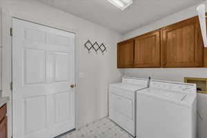 Laundry room featuring light floors, cabinet space, and washing machine and dryer