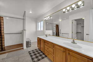 Bathroom featuring double vanity, a shower with curtain, light tile patterned floors, and recessed lighting