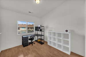 Office with light wood-type flooring and lofted ceiling