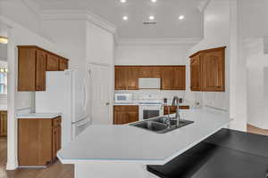 Kitchen with wood finish cabinetry, crown molding, a peninsula, light wood-style floors, and recessed lighting
