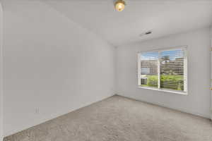 Spare room featuring carpet flooring and lofted ceiling
