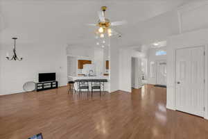 Living room with ceiling fan, light wood-style flooring, lofted ceiling, ornamental molding, and hanging lights