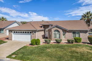 View of front of house featuring an attached garage, a front lawn, concrete driveway, and a tile roof