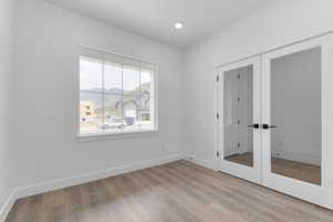 Unfurnished bedroom with french doors, a closet, light wood-style flooring, and a mountain view