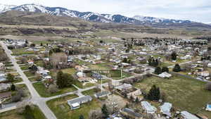 Aerial view of property and surrounding area featuring nearby suburban area and a mountain backdrop