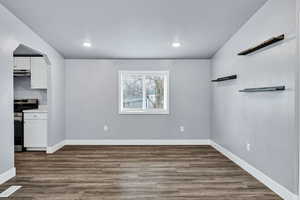 Unfurnished dining area with dark wood-type flooring, arched walkways, and recessed lighting