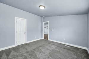 Unfurnished bedroom featuring dark carpet and a textured ceiling