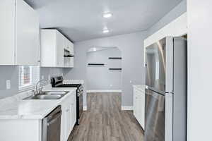 Kitchen featuring stainless steel appliances, light countertops, white cabinets, light wood-type flooring, and a textured ceiling