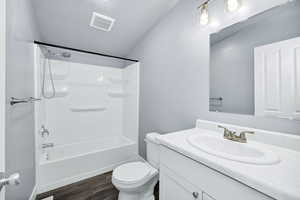 Bathroom featuring vanity, bathing tub / shower combination, and dark wood-style floors