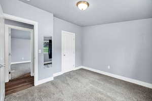 Unfurnished bedroom featuring carpet flooring, a textured ceiling, and a closet