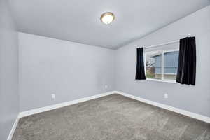 Spare room featuring vaulted ceiling and carpet