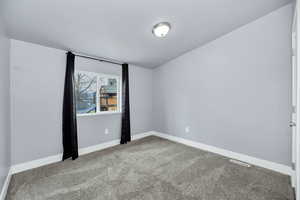 Empty room featuring baseboards and light carpet