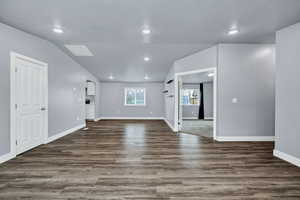 Unfurnished living room with dark wood-style flooring, recessed lighting, and lofted ceiling