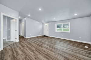 Unfurnished living room with dark wood-style flooring and recessed lighting