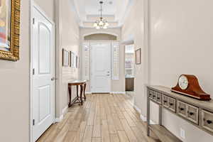 Entryway featuring wood finish floors, a chandelier, and a raised ceiling