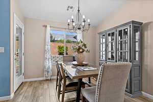 Dining room featuring light wood-style flooring, suspended lighting, a mountain view, and vaulted ceiling