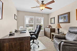 Office with light carpet and ceiling fan