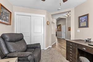 Office area featuring light carpet, a ceiling fan, and hanging lights