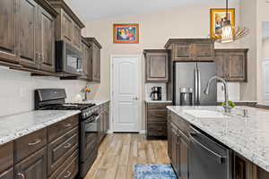 Kitchen featuring decorative backsplash, stainless steel appliances, dark wood finish cabinets, pendant lighting, and vaulted ceiling
