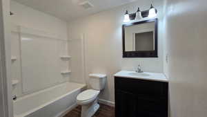 Bathroom with vanity, dark wood-type flooring, and shower / tub combination