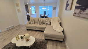 Living area featuring light wood-style flooring and a chandelier