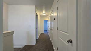 Hall with baseboards and dark carpet