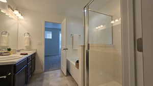 Bathroom featuring double vanity, a garden tub, and a shower stall