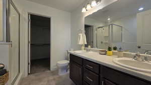Full bath with a stall shower, double vanity, and a spacious closet; Primary bathroom