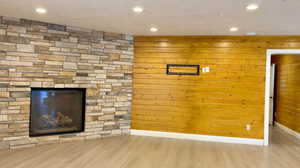 Detailed view of recessed lighting, a fireplace, wood finished floors, and wooden walls