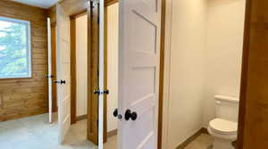 Half bathroom with wood walls and light flooring