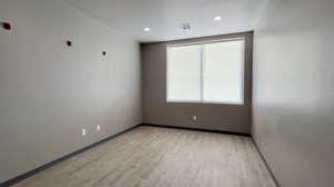 Empty room with light wood-style flooring and recessed lighting