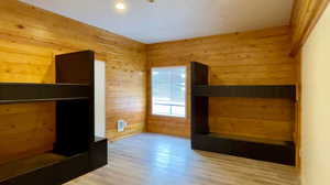 Unfurnished bedroom featuring wood walls and light wood-type flooring