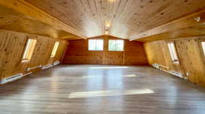 Bonus room featuring wood ceiling, hardwood / wood-style floors, wood walls, and a baseboard heating unit