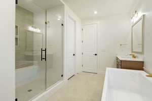 Bathroom with a freestanding bath, vanity, a stall shower, and recessed lighting