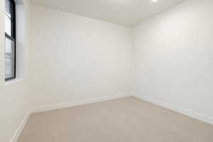Carpeted spare room featuring baseboards